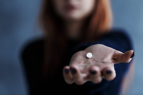 Tolerance, Dependence, and Addiction: What Common Substance Abuse Terms Mean - woman holding a pill