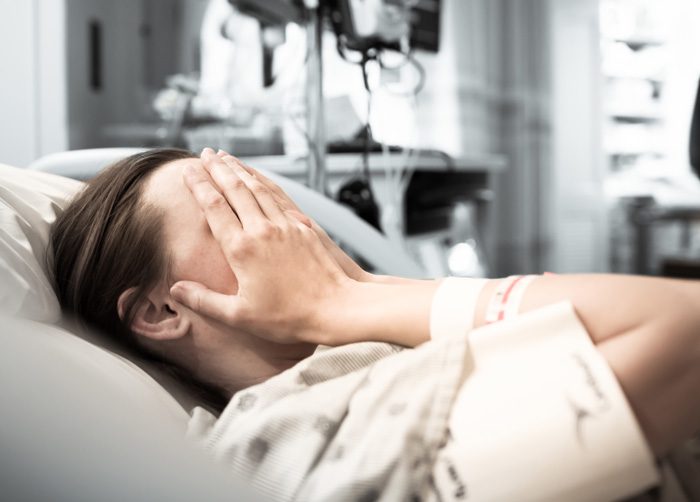 Can Withdrawal Be Fatal - girl in hospital bed with hands covering face