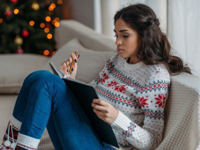 Understanding-How-the-Holiday-Season-Can-Affect-Your-Sobriety - woman in holiday sweater journaling