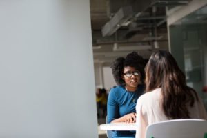 beautiful African American woman talking to brunette woman at table - 12-step