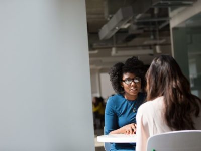 beautiful African American woman talking to brunette woman at table - 12-step