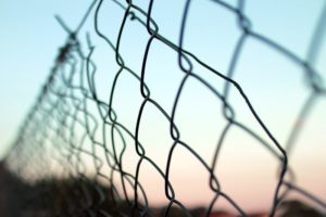 closeup of chain link fence with sunset in background - fears