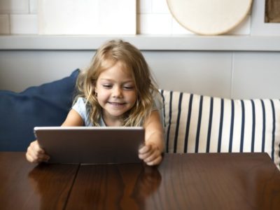 cute little girl smiling holding tablet computer at a table - young children