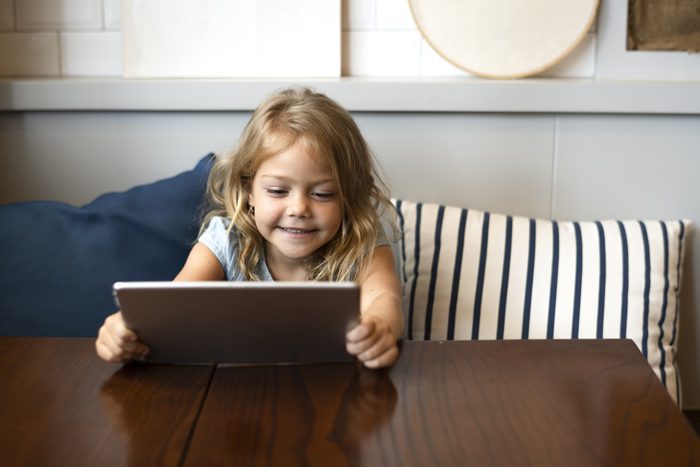 cute little girl smiling holding tablet computer at a table - young children
