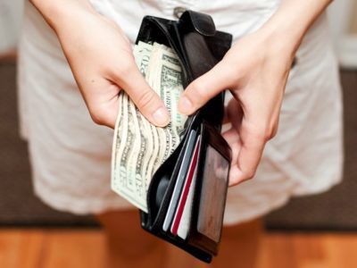 closeup of woman taking bills out of wallet - enabling