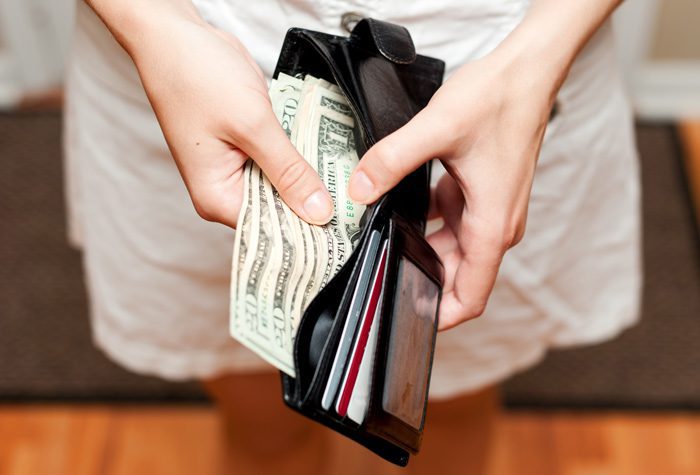 closeup of woman taking bills out of wallet - enabling