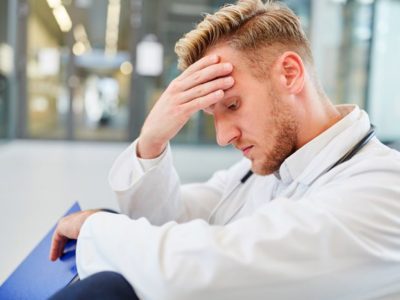 male doctor looking stressed sitting on ground - professionals
