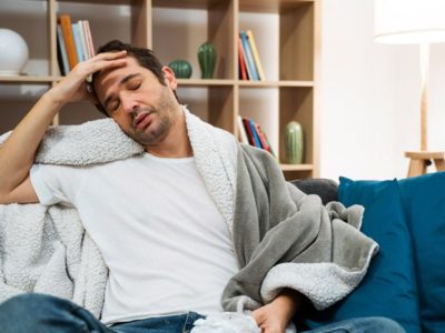Alcohol Withdrawal in Quarantine, Managing Alcohol Withdrawal During Coronavirus Lockdown, sick man sitting on couch at home wrapped in blankets - alcohol withdrawal - quarantine