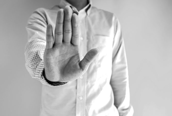 black and white image of man holding his hand out in a stop gesture - HALT - COVID-19