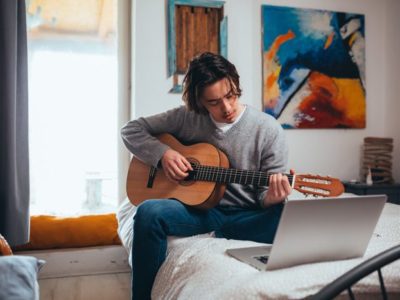 young man sitting in room practicing guitar - creative side