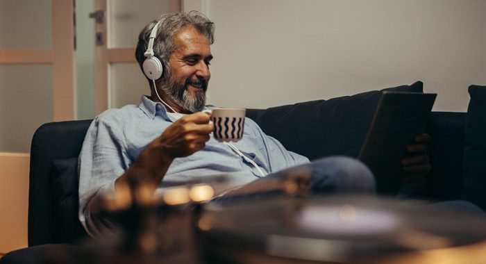 older man at home drinking coffee and listening to music