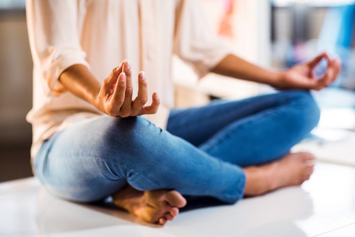 woman sitting on desk or table meditating - emotions