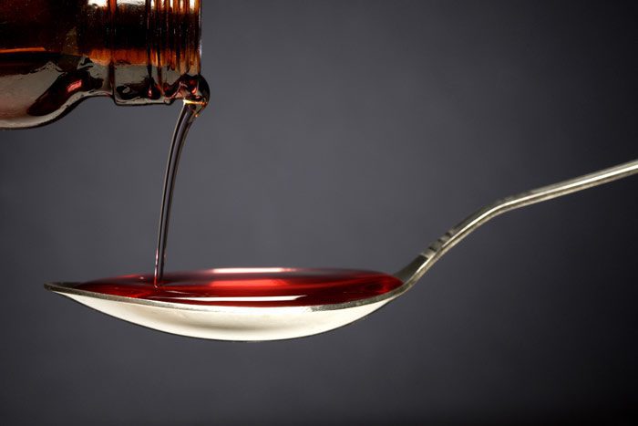 close up of cough syrup being poured into a spoon - codeine cough syrup