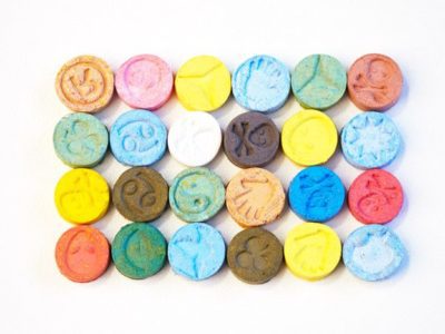 colorful, different ecstasy tablets lined up on white background