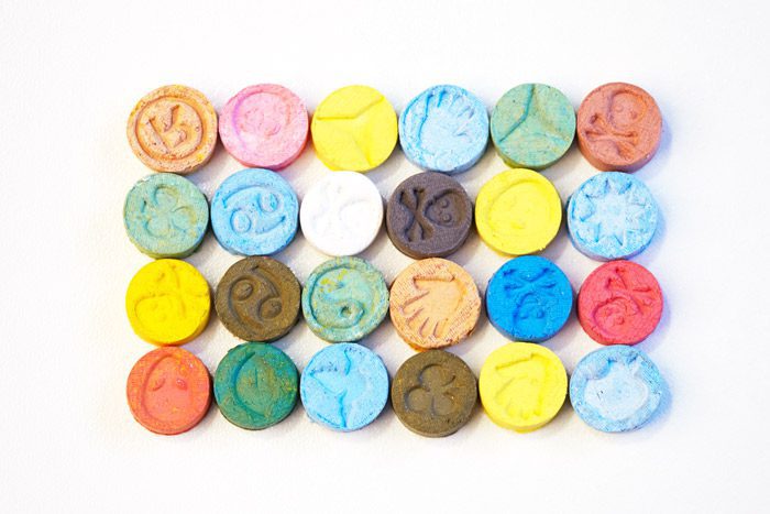 colorful, different ecstasy tablets lined up on white background