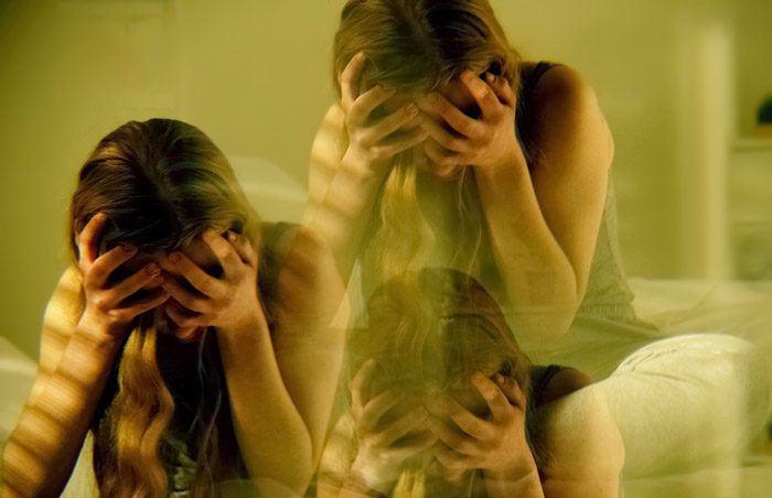 triple exposure image of young girl with her head in her hands - room spinning and high on drugs - club drugs