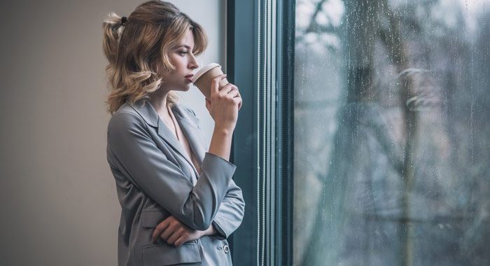 pretty young businesswoman looking out window drinking coffee - willpower and recovery