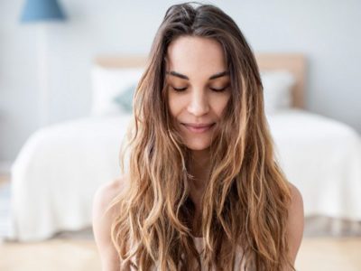 pretty young woman with long hair sitting on the floor of her room with her eyes closed - grounding techniques