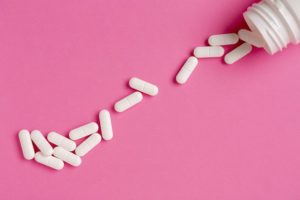 bottle of white pills spilling onto pink background - tramadol addiction