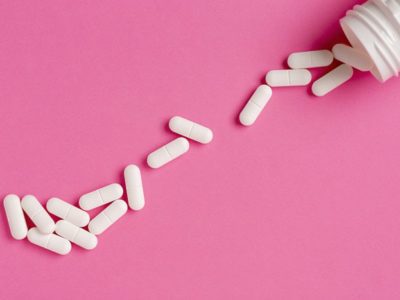 bottle of white pills spilling onto pink background - tramadol addiction