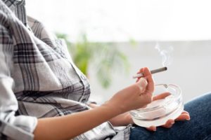 Myths and Facts About Marijuana Use, cropped shot from neck down of older woman in a plaid shirt smoking a marijuana cigarette