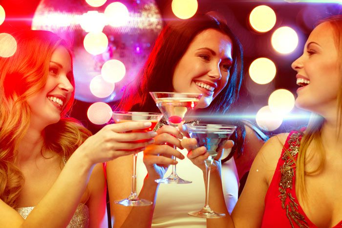 three girlfriends at a bar having cocktails - alcohol