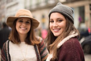 drug and alcohol codependency, codependency, two pretty and stylish young women walking outside together, stopped and smiling at the camera - codependency