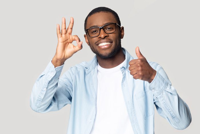 Addiction is a chronic illness, Chronic Illnesses, smiling Black man in glasses giving the thumbs up with one hand and the okay sign, with the other - chronic illnesses