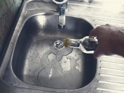 cropped shot of a man's hand pouring liquor down the sink drain - alcohol withdrawal