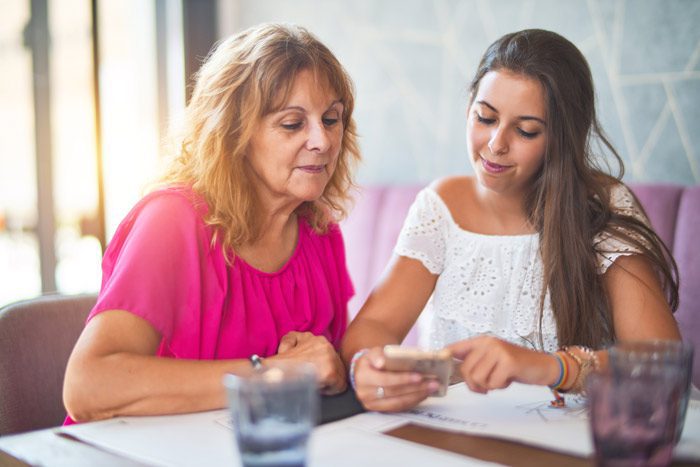 adult child has a drinking problem, beautiful Latina mom and daughter talking and looking at phone - adult child