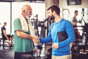 handsome senior man shaking the hand of his trainer or physical therapist - careers