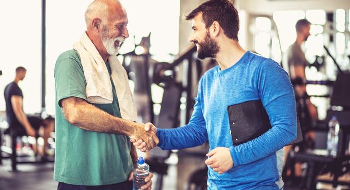 handsome senior man shaking the hand of his trainer or physical therapist - careers