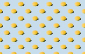 small yellow pills lined up in rows on a light sky blue background - in a wallpaper or wrapping paper style - OxyContin addiction