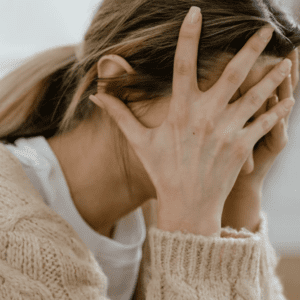 A woman with her hands over her face.