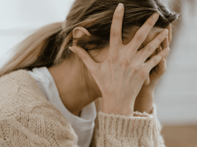 A woman with her hands over her face.