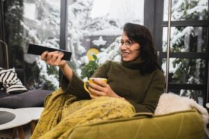 Young woman watching TV and enjoying coffee at home.