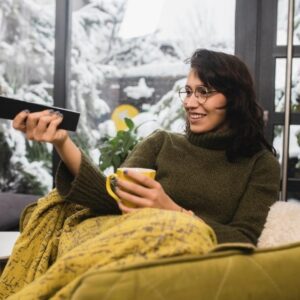 Young woman watching TV and enjoying coffee at home.