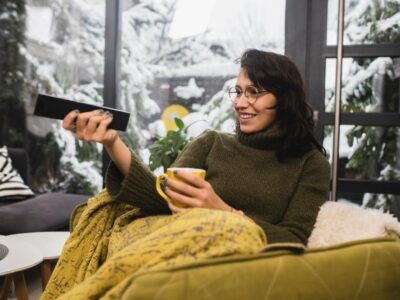 Young woman watching TV and enjoying coffee at home.