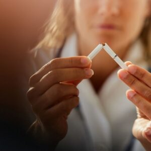 Close up of unrecognizable female doctor tearing cigarette while advocating for anti smoking.