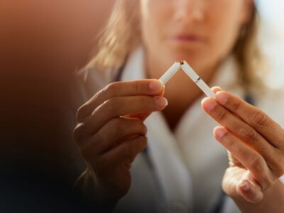 Close up of unrecognizable female doctor tearing cigarette while advocating for anti smoking.