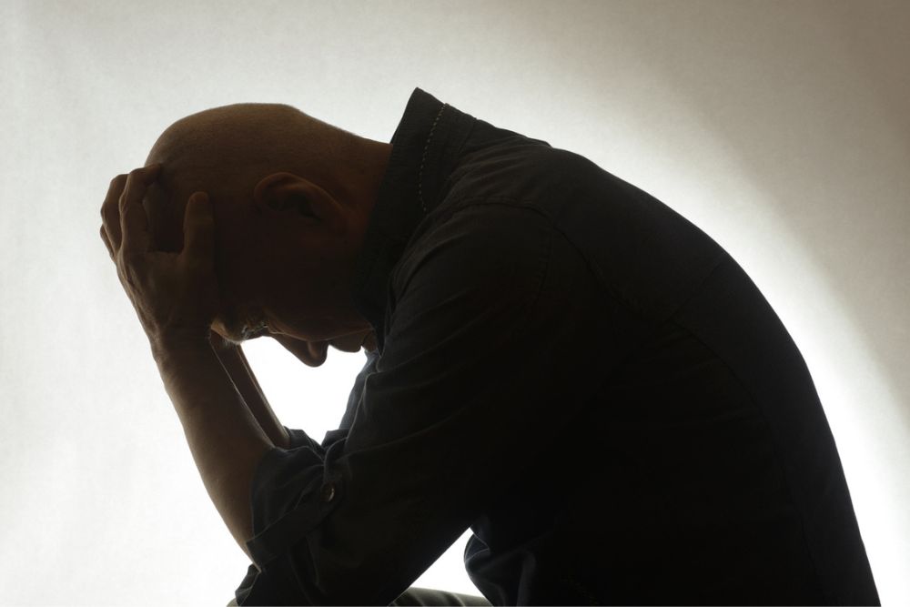Silhouette of a person with their head in their hands.
